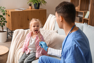 Fototapeta premium Male pediatrician examining little girl with tongue depressor at home