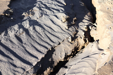 Fototapeta premium Sand texture with deep grooves and shadows. Abstract desert landscape with unique patterns and natural formations.