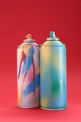 Two spray paint cans on red background