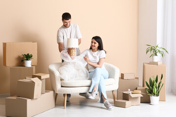 Young happy couple unpacking belongings on sofa in their new house