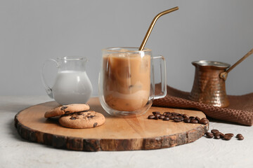 Glass cup of iced latte with sweet cookies and coffee beans on white background