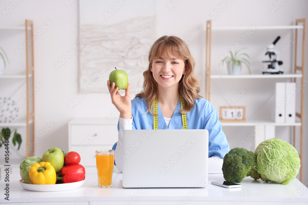 Canvas Prints Female nutritionist with apple at table in office