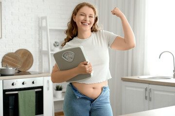 Happy young woman in tight jeans with scales at home. Weight gain concept
