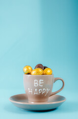 Coffee cup with chocolate eggs on a blue background.
