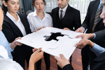 Multiethnic business people holding jigsaw pieces and merge them together as effective solution...