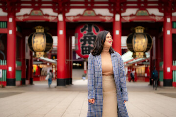 Obraz premium A young Latina woman takes a photo at Sensoji Temple in Asakusa, Tokyo, Japan, capturing the vibrant scenery.