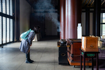 Unrecognizable young Latina woman participating in a water purification ritual at Zojoji Temple in Tokyo, Japan.