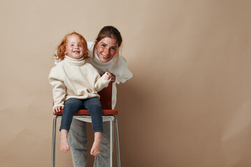 Family relaxation woman and girl sitting on chair against beige background, vacation, leisure, lifestyle, comfort, cozy, home