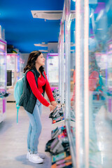 Young Latina woman smiling and playing arcade games in Akihabara, Tokyo, Japan, surrounded by...