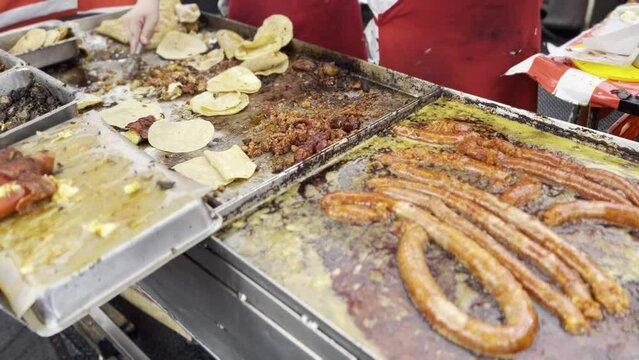 Taquero en CDMX prepara taco de longaniza. Plancha con aceite hirviendo.