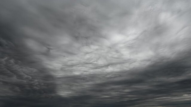 Time lapse of an ominous looking sky full of light to dark gray storm clouds.  The clouds are drifting from left to right.
