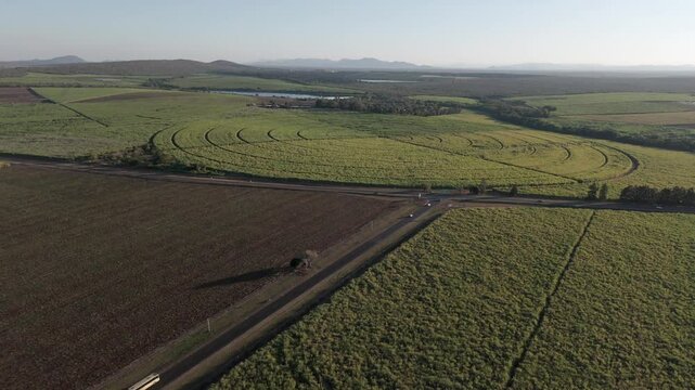 Drone view of Sugarcane and pepper farms in a patchwork quilt, divided by a main road with vehicles driving towards a T- junction. Mpumalanga, South Africa.