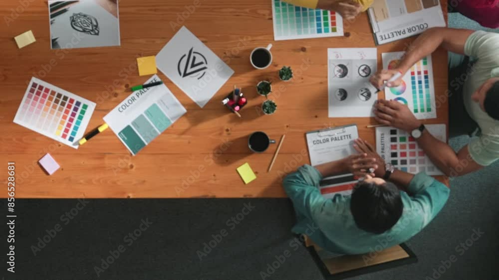 Poster top down aerial view of designer looking at tablet while project manager choosing color palettes. to