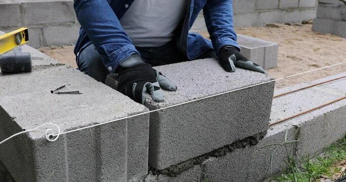 Construction worker laying expanded clay blocks. Foundations of a house, the frame of a new house in the process of construction