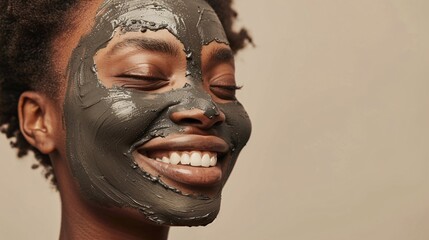 A model with a clay face mask applied, smiling at the camera