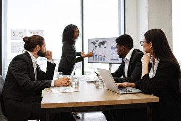 Business professionals in modern office setting having meeting with presentation. Corporate team analyzing data on presentation screen, discussing strategies, and collaborating on project.