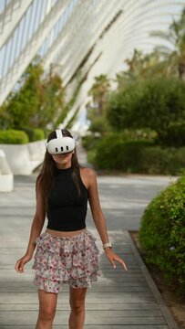 A woman enjoys virtual reality technology in a park, surrounded by greenery and nature