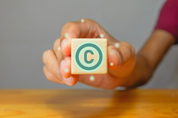 Man holding a wooden block with copyright symbol. Copyright or patent intellectual property concept.