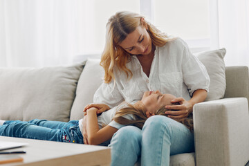 Mother and child bonding time smiling woman with little one on lap relaxing on a cozy couch