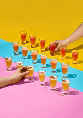 Vibrant Colorful Shots on Bright Background with Hands Reaching for Drinks