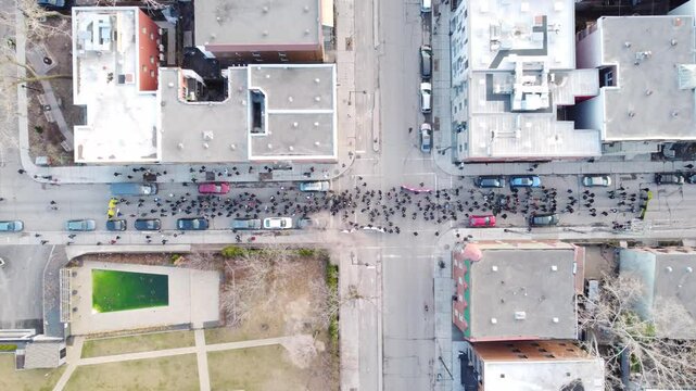 A top down drone view of Montreal Street with people walking, buildings on both sides, and parked cars.