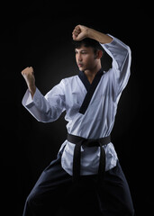 Taekwondo black belt athlete poses in a poomsae pose against a black background