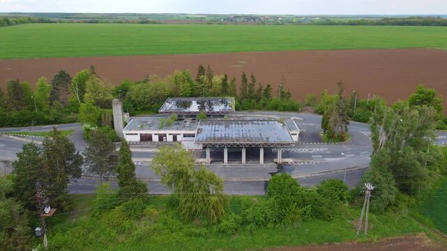 Drone focuses on old border crossing Hataratkelo - Bucsu between Austria and Hungary on highway. zooming in to background farmland under cloudy skies