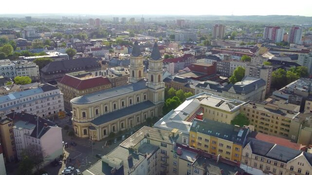 Drone moves forward, Ostrava's cityscape view featuring buildings, streets, skyline, trees on sunny day.