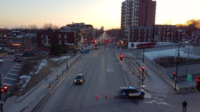 Montr&eacute;al, Qu&eacute;bec, Canada. Drone push in to highway with cars, police van, bus, with city buildings in evening.