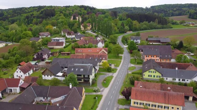 Drone moves forward in a cinematic shot, view from street in Sebersdorf town to Obermayerhofen Castle. Austria.