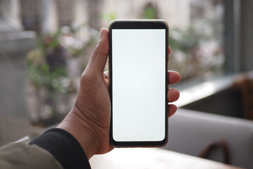 A hand holds a smartphone with a blank screen, suitable for app or website mockups