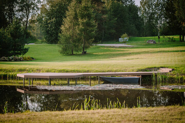 Blome, Latvia - September 11, 2023 - Small dock with a rowboat on a tranquil pond, surrounded by...