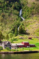 picturesque landscape of a rural village with a waterfall and lush green hills in Norway.