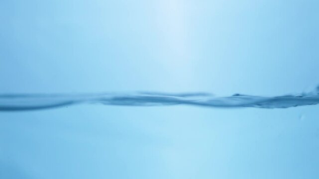 Waves of crystal clear blue mineral water, creating some tiny bubbles and droplets of in a water tank.