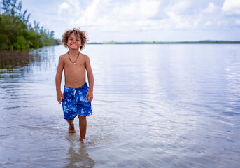 Handsome, smiling, African American boy walking along an ocean lagoon in Florida, Enjoying a fun day in the water 