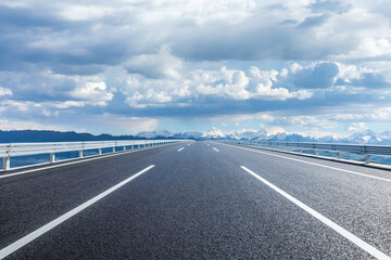 Straight asphalt highway road and snow mountains with sky clouds natural landscape. car background.