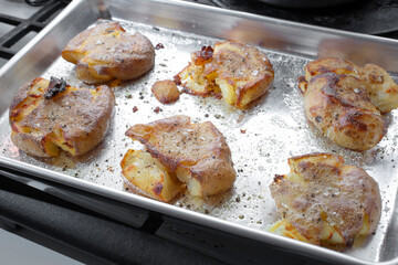 A view of a baking tray of smashed potatoes.