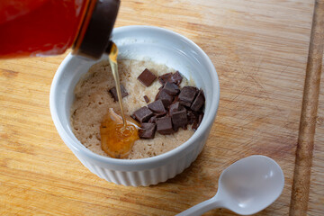 A view of a bottle of honey pouring  into a microwave cookie in a ramekin.