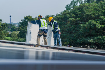 Worker Technicians are working to construct solar panels system on roof. Installing solar photovoltaic panel system. Men technicians carrying photovoltaic solar modules on roof.