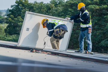 Worker Technicians are working to construct solar panels system on roof. Installing solar photovoltaic panel system. Men technicians carrying photovoltaic solar modules on roof.