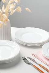 Stylish table setting with white dishware on white tablecloth