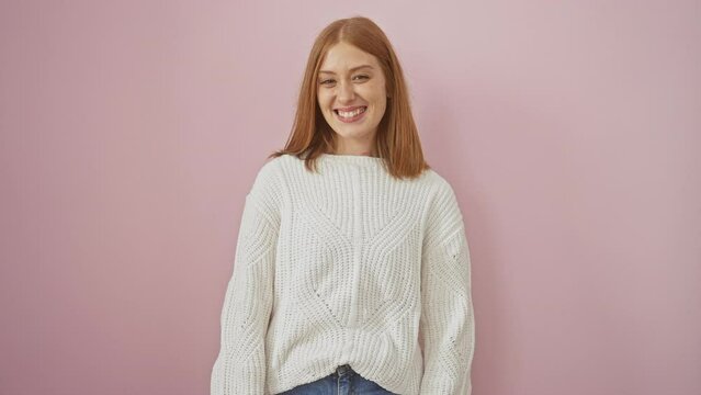 Madcap joy! redhead young woman sticks tongue out playfully, donning sweater, standing against isolated pink background. her amusing face adds a fun, happy twist to this crazy gesture!