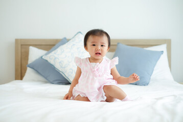 Fototapeta premium Cute little asian girl sitting and crying for my mother to come near on the bed at home.