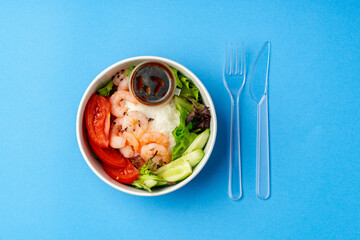 Top view of fresh poke bowl on blue background