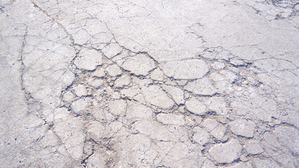 Cracks and broken texture on surface of the old badly damaged concrete street surface