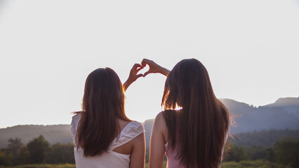 Silhouette couple hands raised up make heart shape on beautiful evening landscape background....