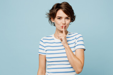 Young secret woman she wears striped t-shirt casual clothes say hush be quiet with finger on lips...