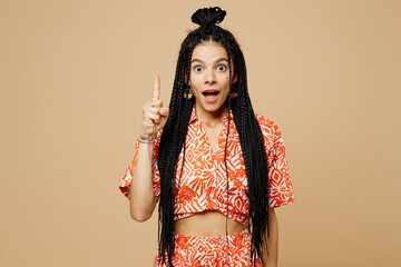 Young shocked surprised Latin woman she wears orange casual clothes holding index finger up with great new idea look camera isolated on plain pastel light beige background studio. Lifestyle concept.