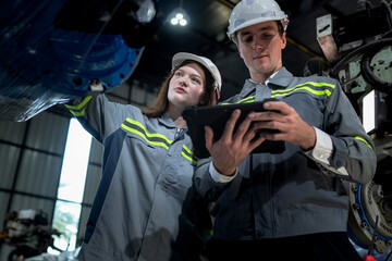 team engineers inspecting on machine with smart tablet. Worker works at heavy machine robot arm. The welding machine with a remote system in an industrial factory. Artificial intelligence concept.