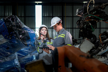 team engineers inspecting on machine with smart tablet. Worker works at heavy machine robot arm. The welding machine with a remote system in an industrial factory. Artificial intelligence concept.
